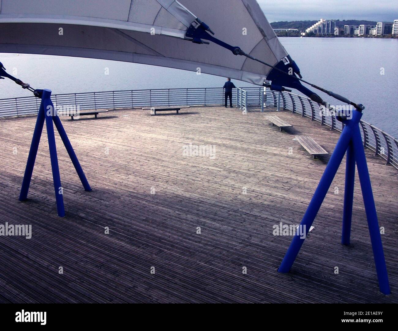 Ein Mann blickt über Cardiff Bay, Wales, uk, mit Segeln im Hintergrund, eine Erinnerung an, als Kapitän Scott zum Südpol segelte. Stockfoto
