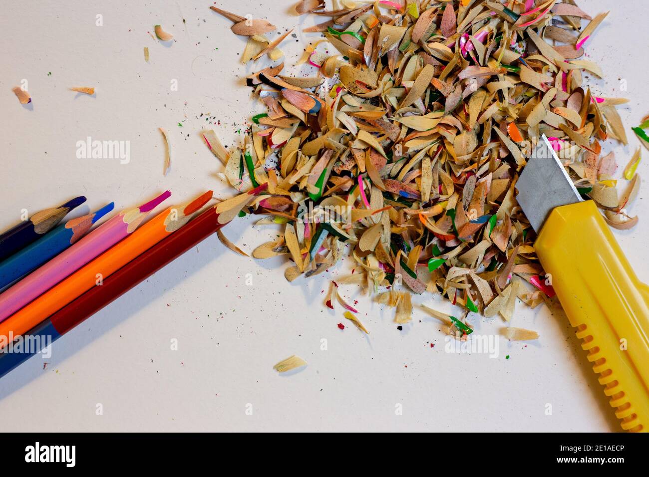 Buntstifte, Späne auf weißem Grund und ein Schreibwarenmesser Stockfoto
