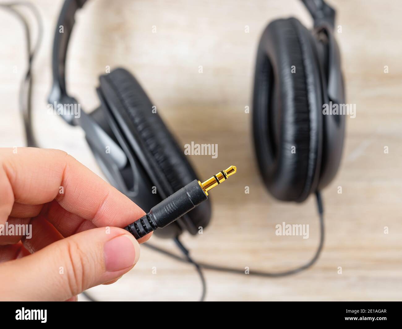 Finger holg golden TRS-Buchse von schwarz verdrahtet über Ohr Kopfhörer. Vergoldete Stecker für hochwertige Audioqualität. Modernes Gadget für das Hören von Musik. Stockfoto