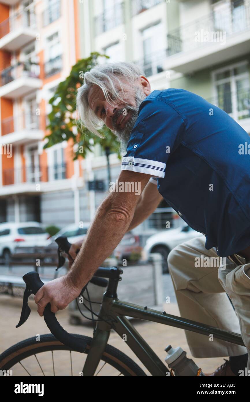 Vertikal beschnitten Porträt eines Senior stilvolle bärtige Mann Radfahren In der Stadt Stockfoto