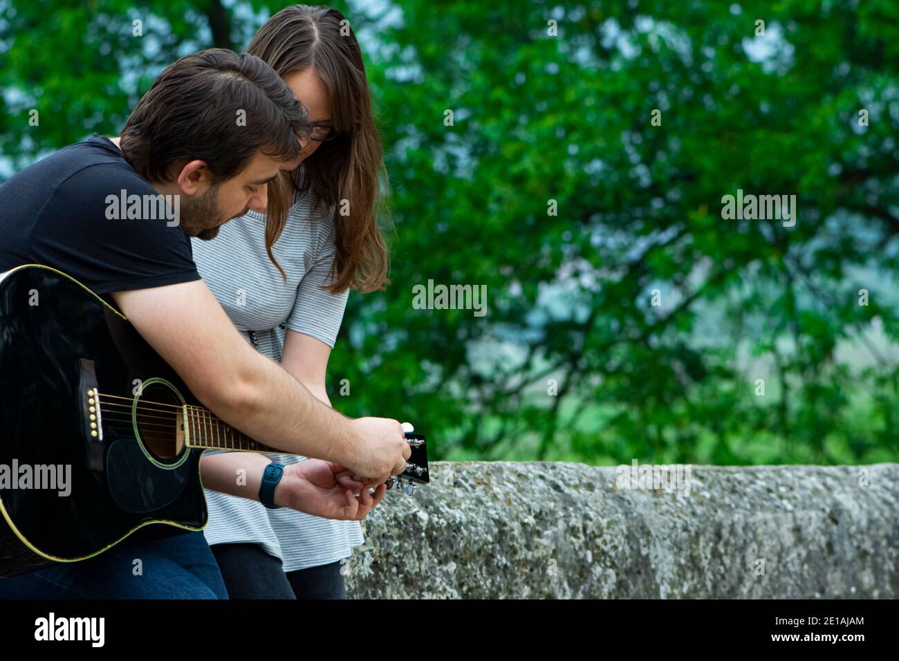 Bruder lehrt Schwester Gitarre in der Natur zu spielen Stockfoto