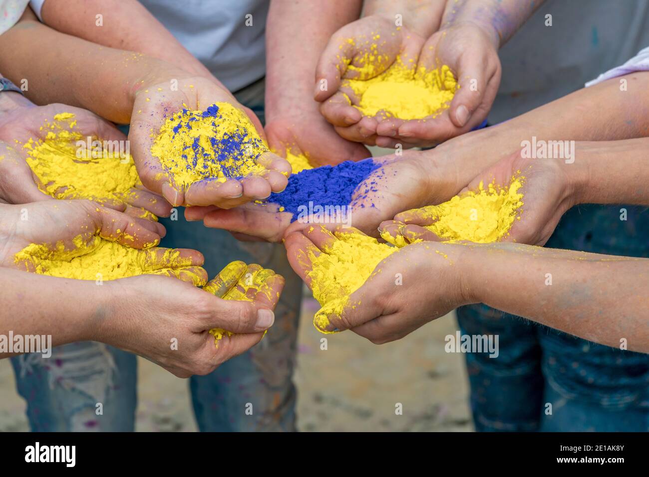 Einige weibliche Hände mit gelbem und blauem Pigmentpulver Stockfoto