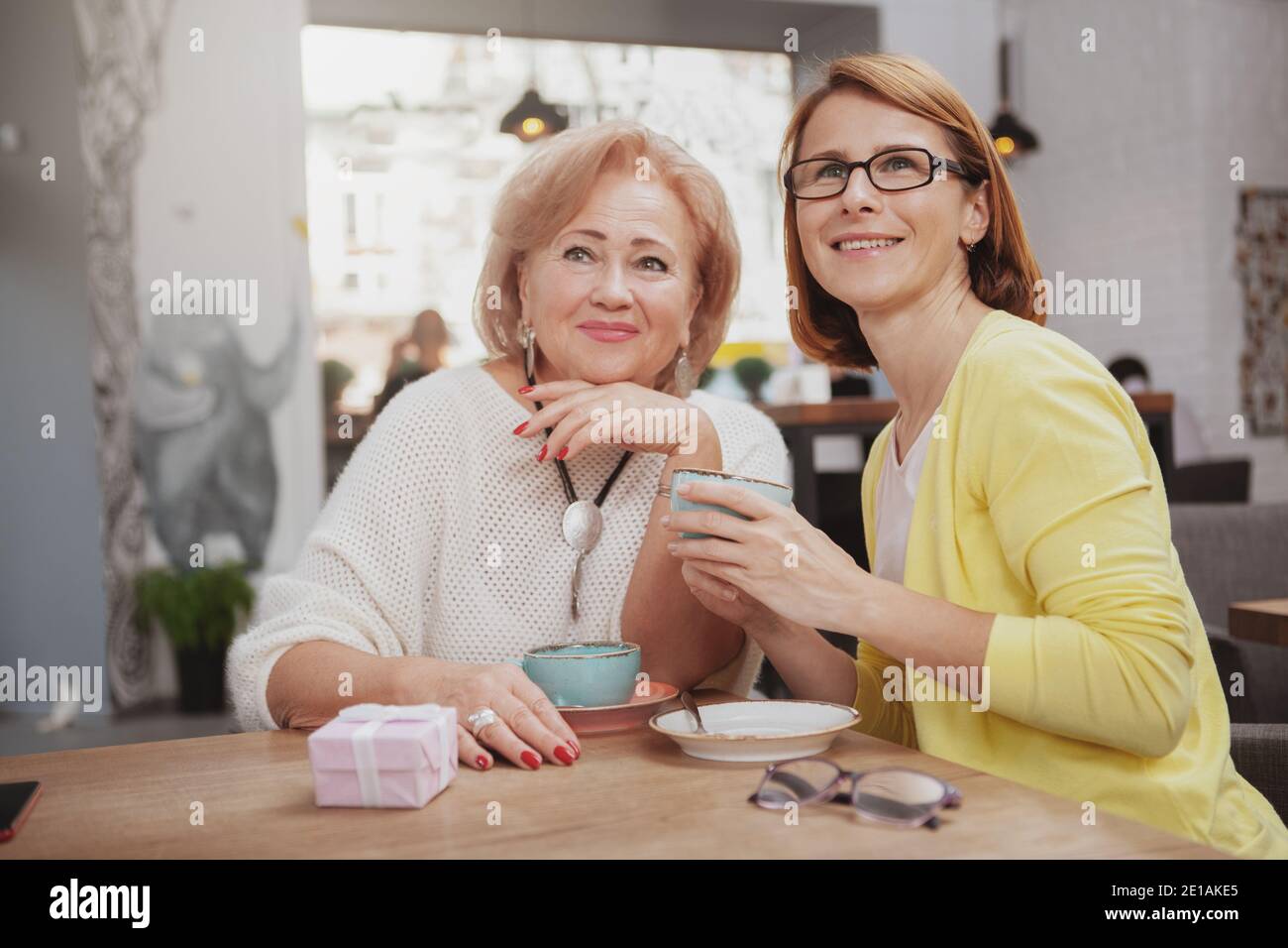 Glückliche ältere Mutter und ihre Erwachsene Tochter beim Kaffee zusammen im Café. Ältere Frau trifft ältere Mutter zum Frühstück Stockfoto