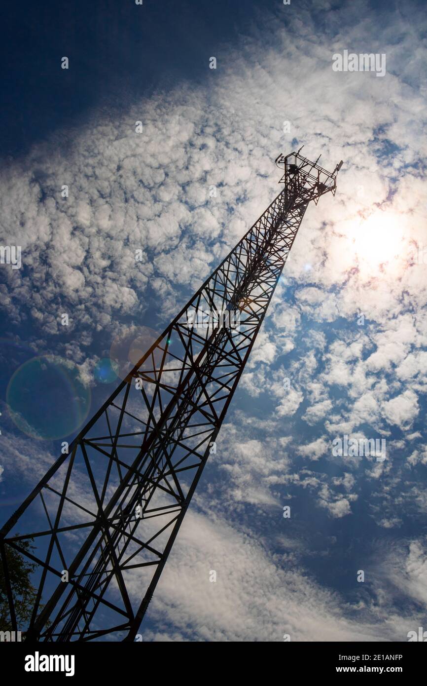 Eine sehr sehr hohe Telekommunikationsantenne mit einem Bottom-up-Winkel Ansicht und eine offensichtliche Perspektive aus dem Boden, mit einem sonnigen Tag und blauen Himmel hinten Stockfoto