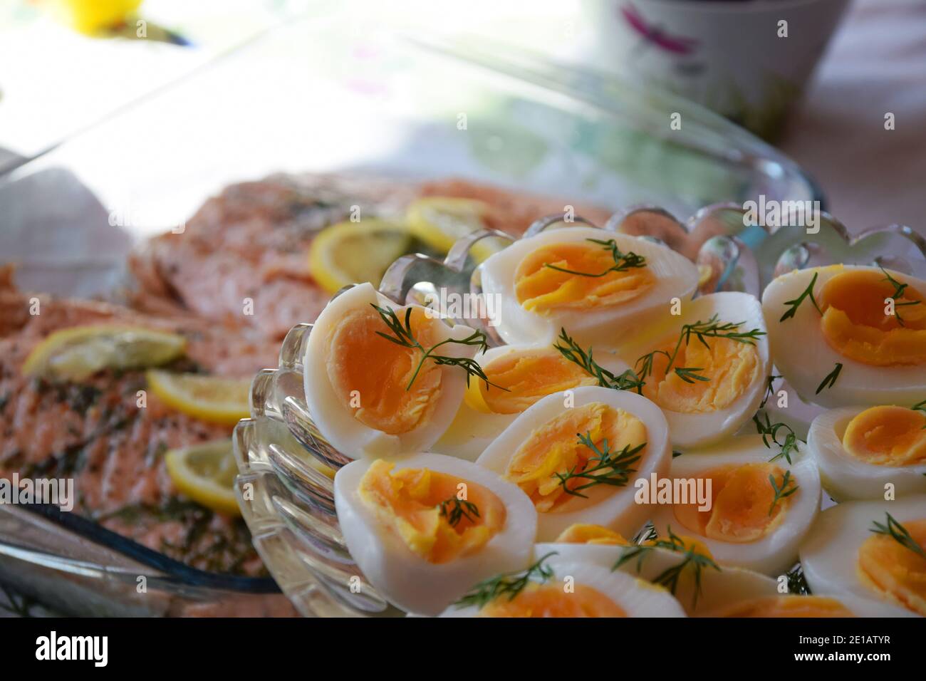 Konzentrieren Sie sich auf gesunde gekochte Eier in zwei Hälften geschnitten, mit etwas frischem Dill dekoriert. Im Hintergrund wird Lachs gekocht, traditionelle schwedische Küche zu Ostern Stockfoto