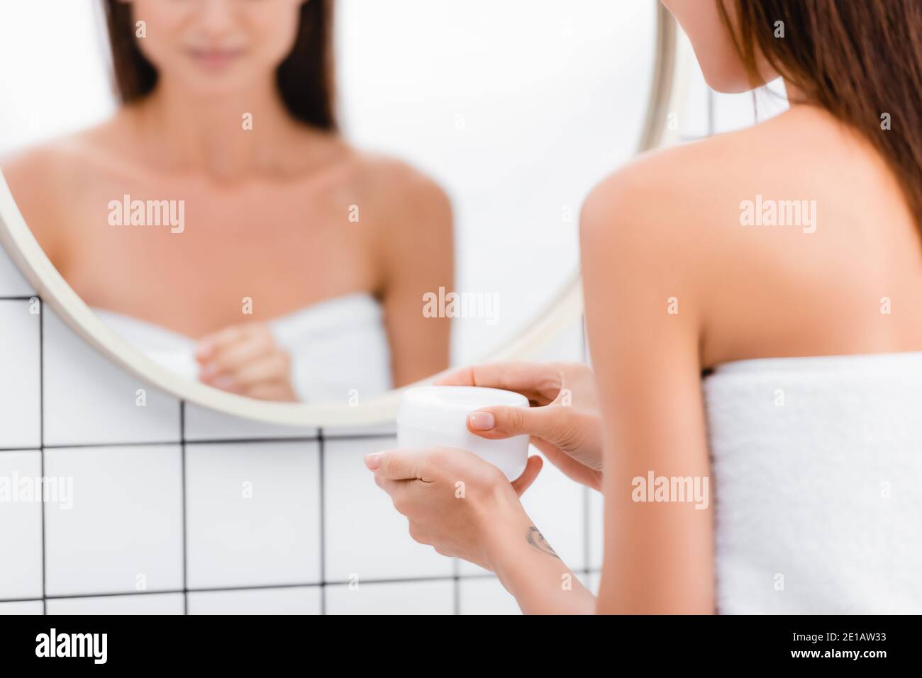 Beschnittene Ansicht der jungen Frau Öffnen Behälter von kosmetischen Creme Nahezu unscharfe Spiegelung im Spiegel Stockfoto