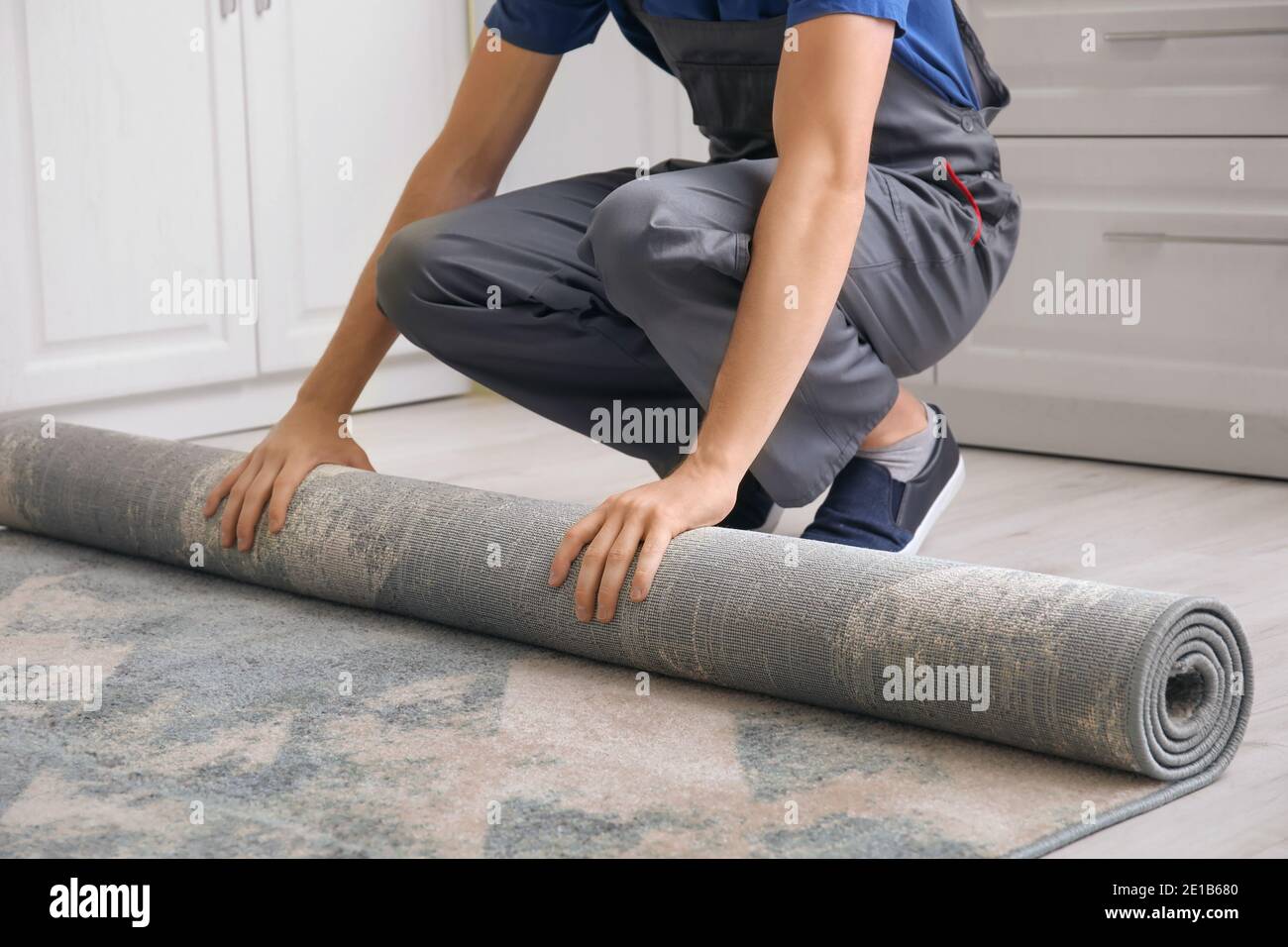 Mann rollt Teppich auf dem Boden im Zimmer Stockfotografie - Alamy