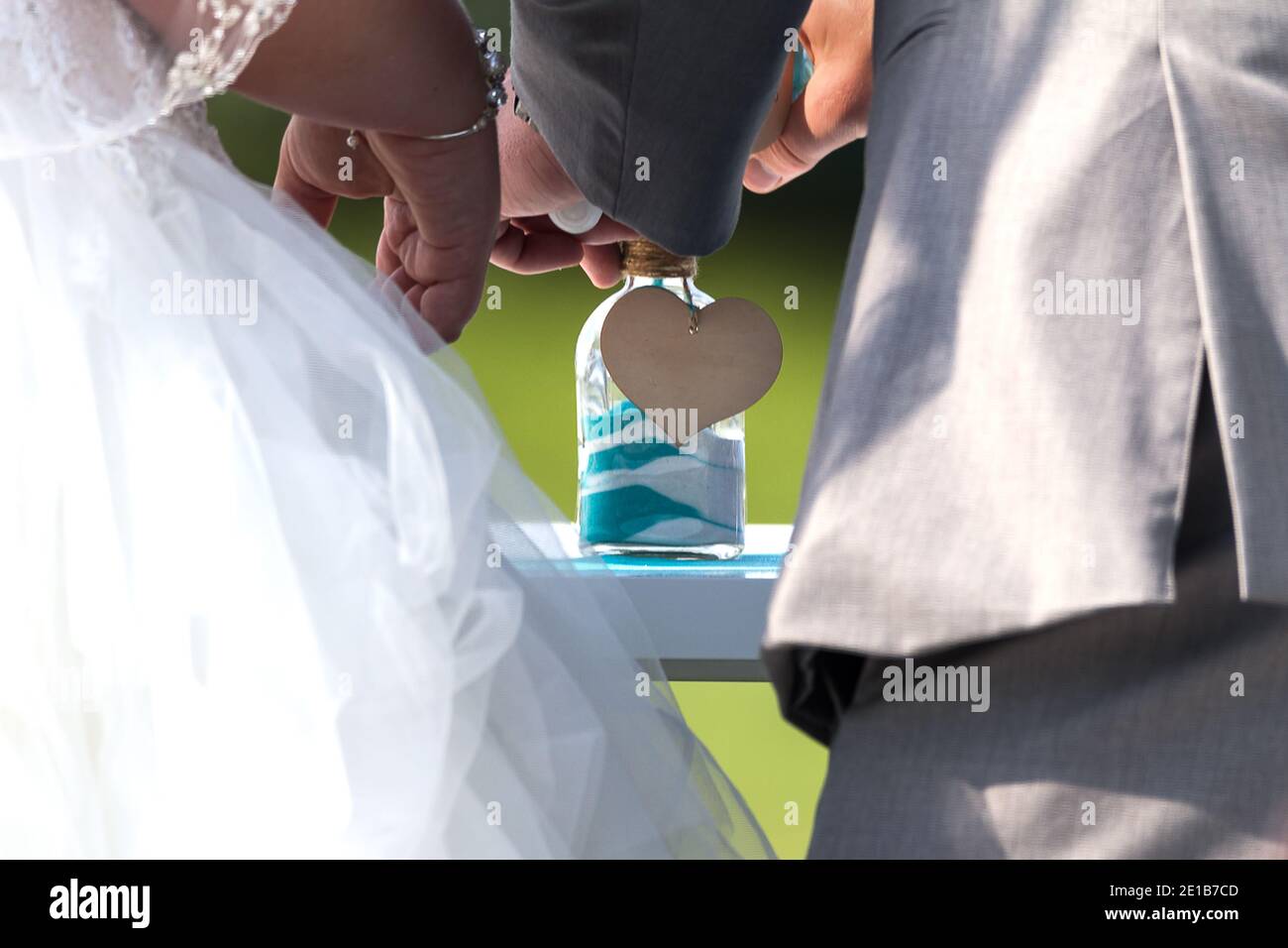Ein Paar, das während ihrer Hochzeitszeremonie in einem Sandritual Sand zu einem Glas hinzufügt. Platz für Kopien Stockfoto