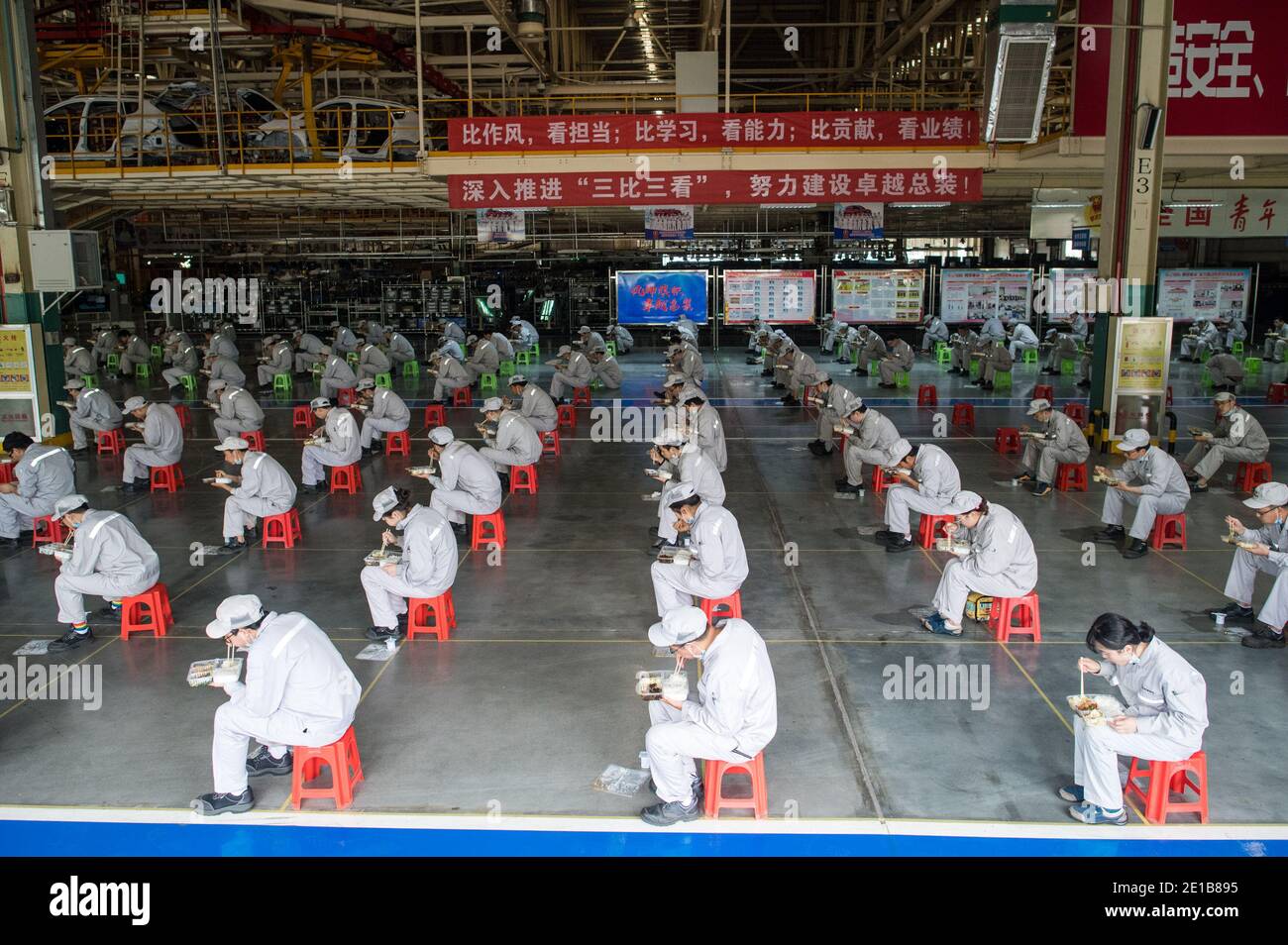 Peking, Chinas Provinz Hubei. März 2020. Arbeiter essen zu Mittag, während sie einen Abstand von zwei Metern in der Werkstatt der Dongfeng Personenwagen Gesellschaft in Wuhan, zentralchinesische Provinz Hubei, 24. März 2020 halten. Quelle: Xiao Yijiu/Xinhua/Alamy Live News Stockfoto