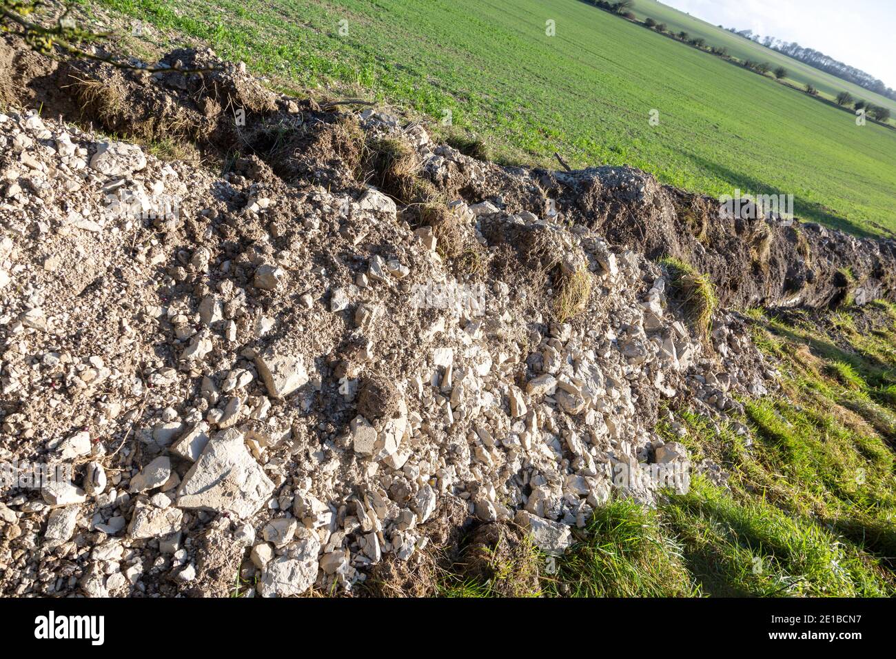 Felsfragmente, die aus dem Entwässerungsgraben auf Ackerland auf Kalkabfällen, Wiltshire, England, Großbritannien, ausgegraben wurden Stockfoto