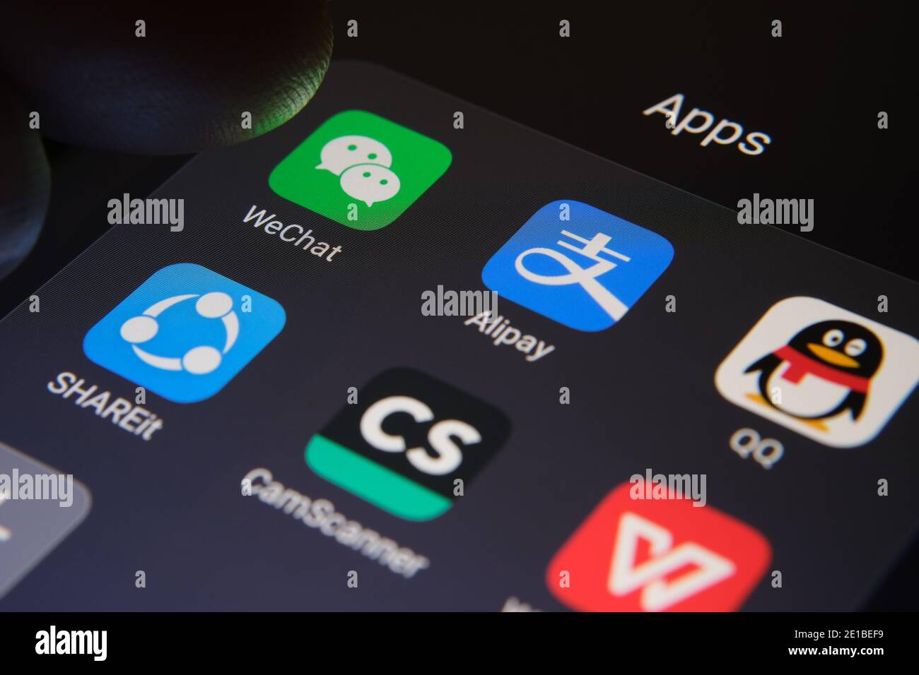 Stafford, Großbritannien - 6. Januar 2021: Alipay, WeChat, QQ, SHAREit, CamScanner, WPS Office-Apps auf dem Bildschirm und verschwommener Finger auf der Oberseite des Th Stockfoto