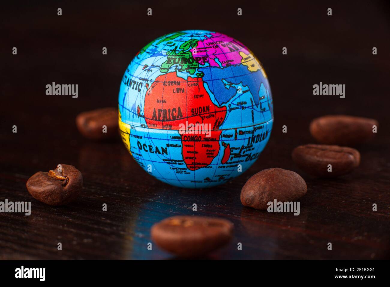 Globus Erde Miniatur mit Kaffeebohnen. Äthiopien ist der Ursprung des Kaffees. Isoliert auf schwarzem Hintergrund. Stockfoto