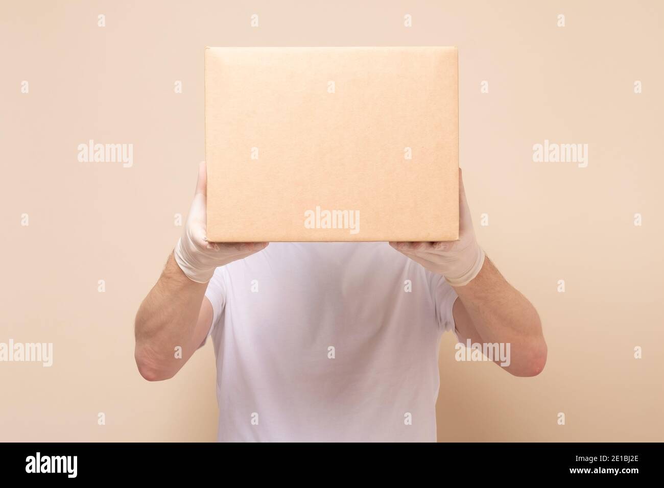 Delivery Mann hält Karton in medizinischen Gummihandschuhen. Online-Shopping und Express-Lieferung . Quarantäne Stockfoto