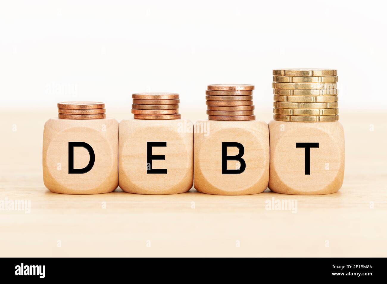 Schuldenkonzept. Holzblöcke mit Text und Münzen auf Holztisch. Kopierbereich weißer Hintergrund Stockfoto