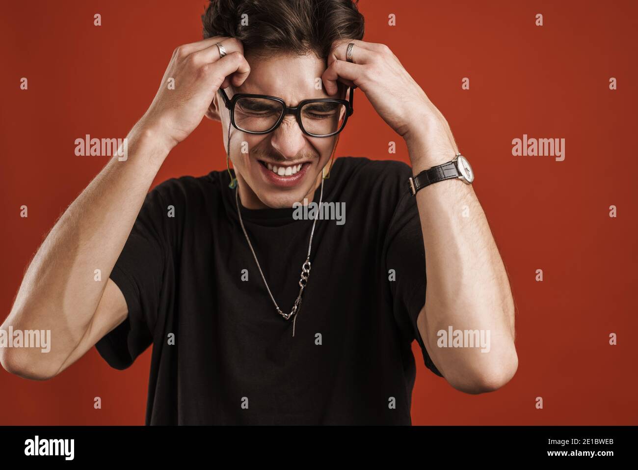 Wütend junge Hipster Kerl gestikulieren mit Händen isoliert über rot Hintergrund Stockfoto