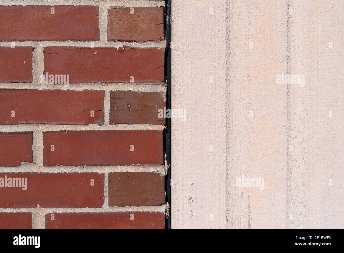 Nahansicht einer Ziegelwand, die neben einer gegossenen Außenbetonwand mit einer Ausdehnungsfuge errichtet wurde. Stockfoto