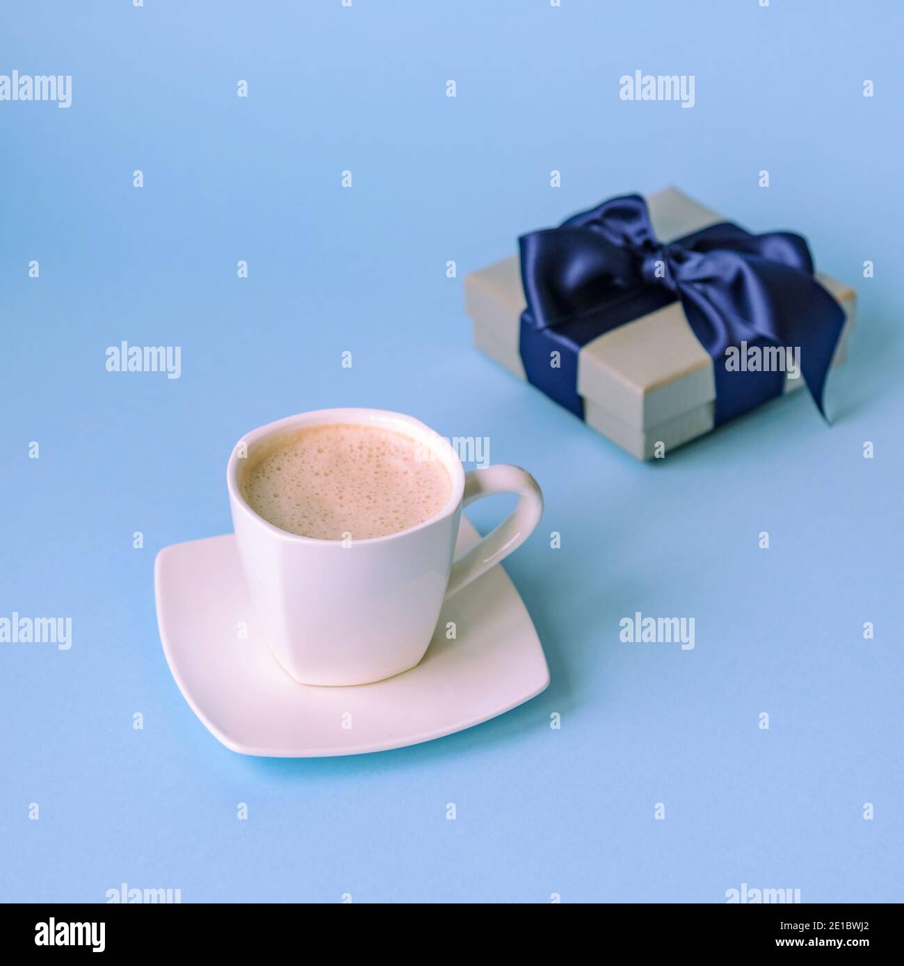 Tasse Kaffee und Geschenk in einer Box auf klassisch blauem Hintergrund. Valentinstag, Geburtstag oder Womens Day Konzept. Stockfoto