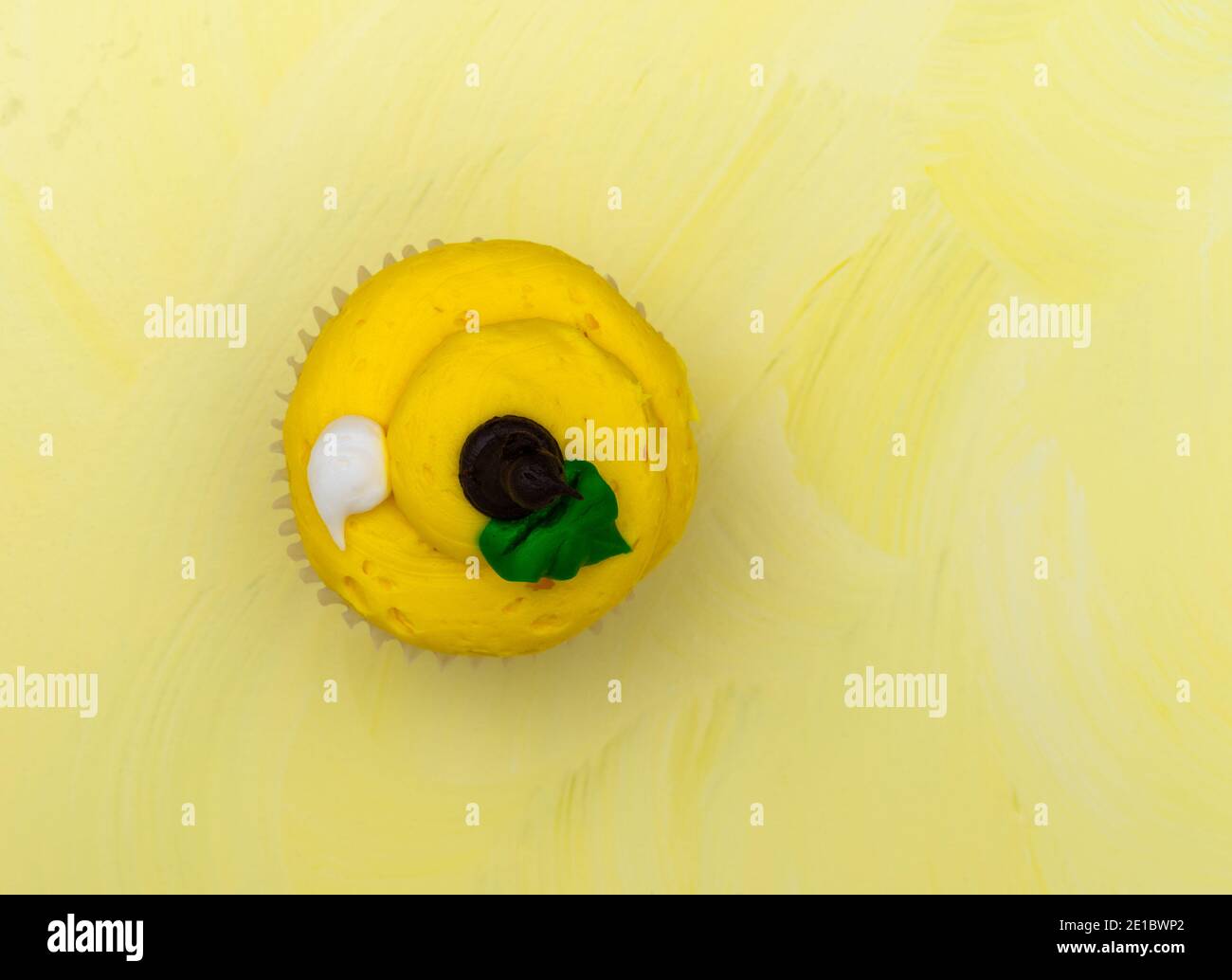 Blick von oben auf einen frisch mattierten Cupcake auf gelbem Hintergrund. Stockfoto