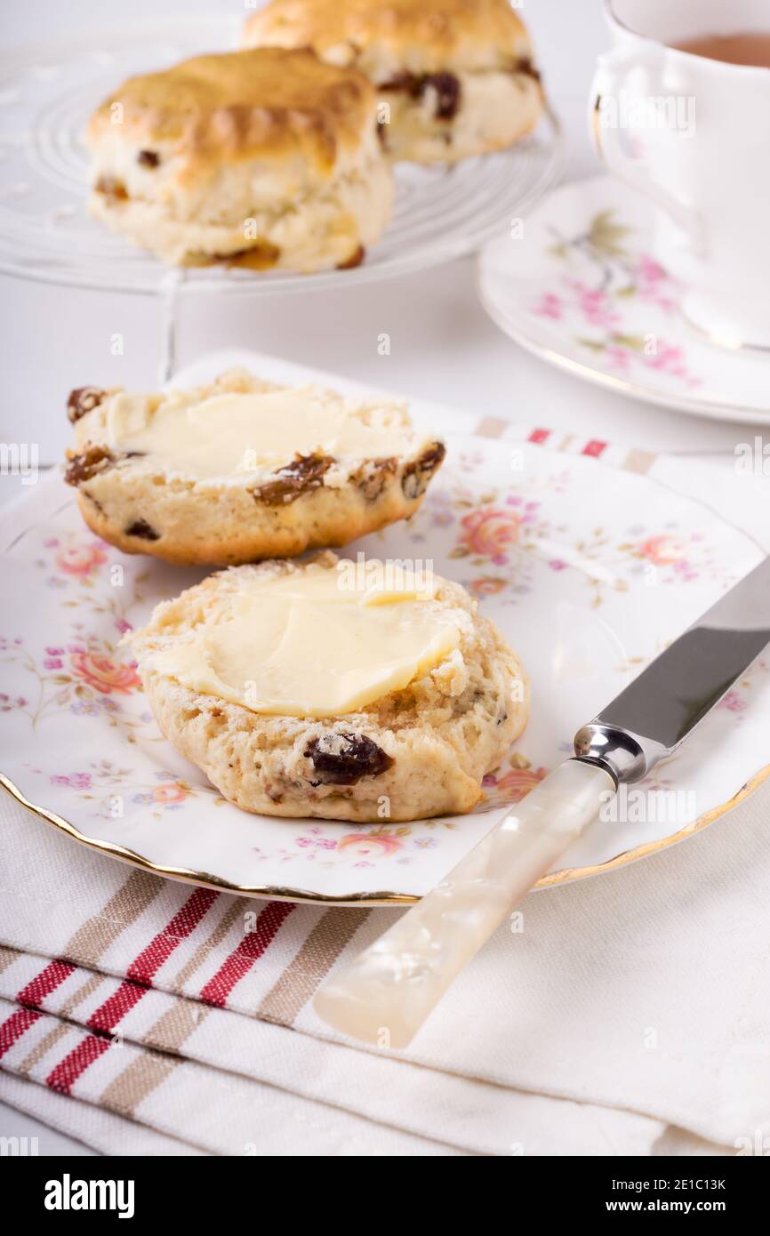 Scones ein klassischer britischer Kuchen gefüllt mit Sultaninen und Rosinen Und wird oft während des Nachmittagstees gebuttert serviert Stockfoto