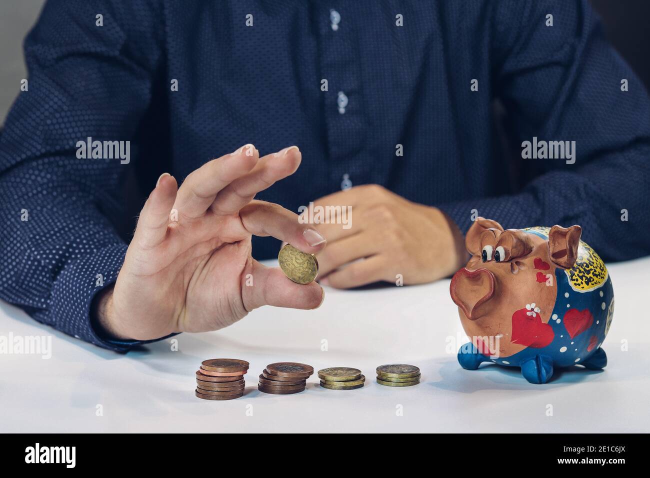 Hypothekenbanker zeigt Geld, wie er in einem kleinen Sparschwein setzt. Geschäftsplan. Der Finanzberater erklärt dem Kunden die Konditionen des Darlehens. Stockfoto