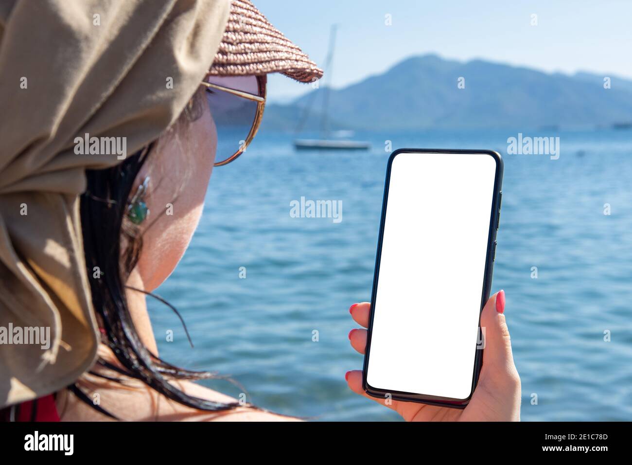 Mockup Handy Urlaub am Meer. Frau Hand hält Handy mit Blank-Bildschirm gegen Sea Beach Outdoor. Roaming im Urlaub. Smartphone in der Hand Stockfoto