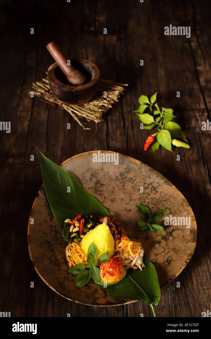 Nasi Kuning. Indonesische festliche Mahlzeit mit Kurkuma-Reis mit Beilagen. Stockfoto