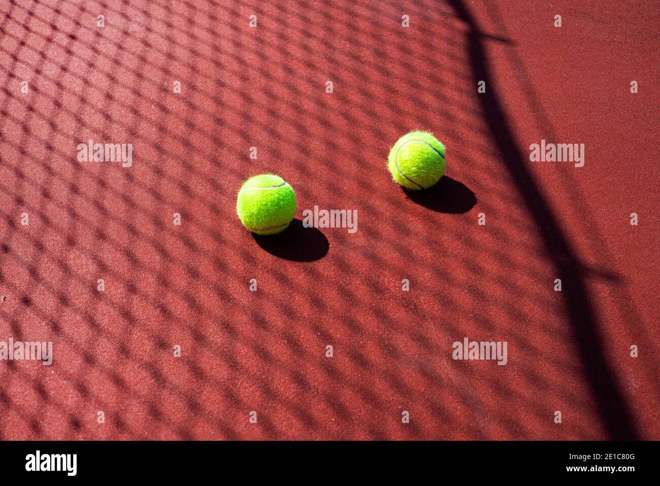 Zwei Tennisbälle auf einem Hartplatz in passierbarer Farbe. Netzschatten. Tennis. Stockfoto