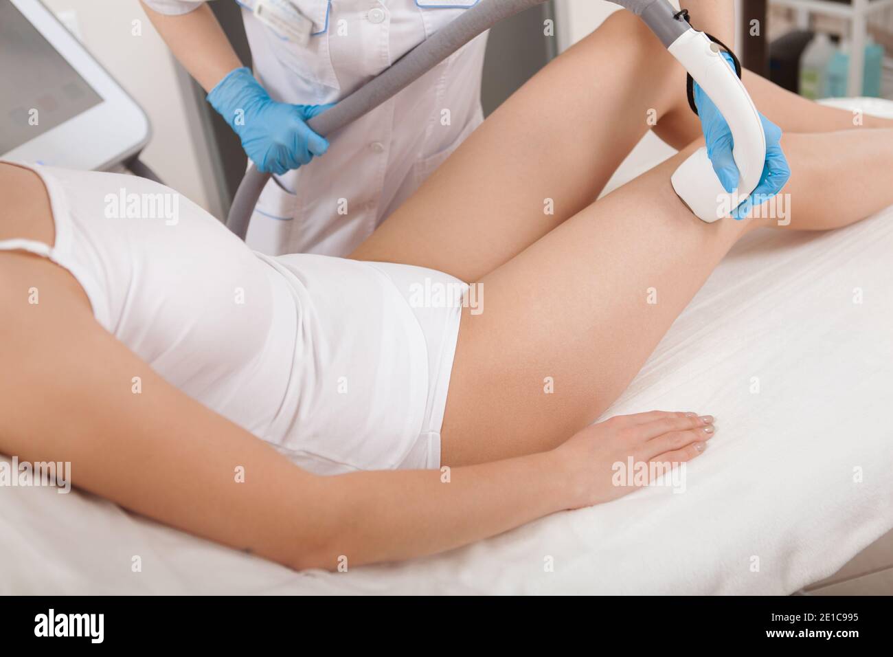 Zugeschnittenes Bild einer Kosmetikerin, die Haare auf dem Bosy des weiblichen Klienten entfernt, mit Laser-Haarentfernungsgerät Stockfoto