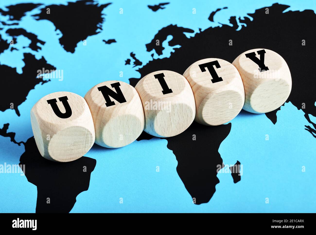 Das Wort Einheit geschrieben auf Holzwürfel auf Weltkarte Hintergrund. Internationale Teamarbeit, Allianz, Zusammenarbeit oder Kommunikation rund um den Globus Stockfoto