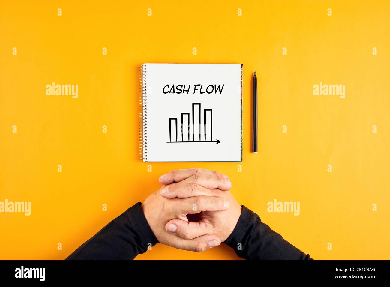 Hände eines Geschäftsmannes und ein Notizbuch mit dem Wort Cash Flow und einem Chart darauf geschrieben. Konzept der Corporate Cashflow-Analyse. Stockfoto