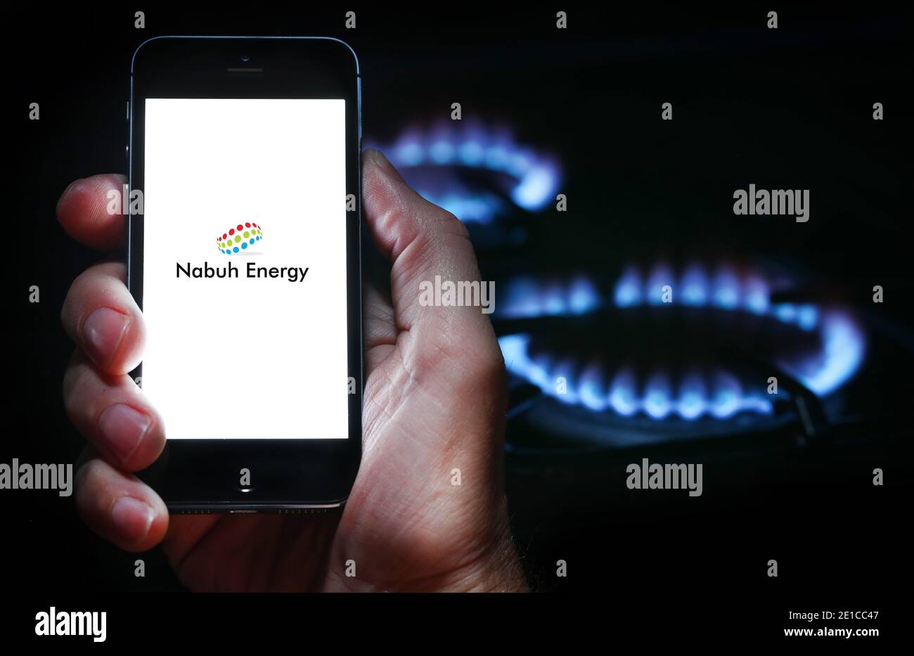 Ein Mann, der sich die App für das Energieunternehmen Nabuh anschaut Auf seinem Telefon vor seinem Gasherd (Nur für redaktionelle Zwecke) Stockfoto