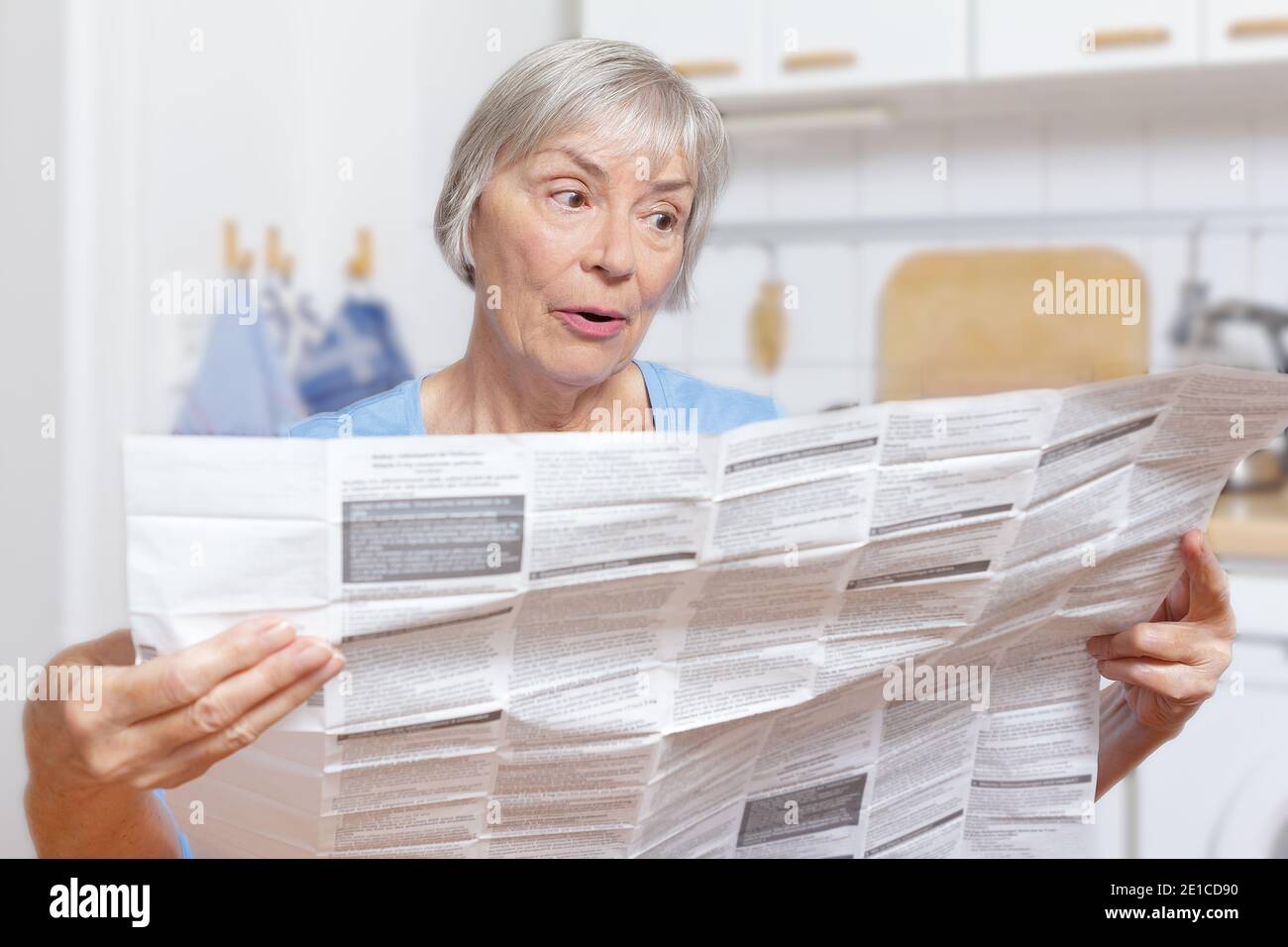 Staunende ältere Frau mit großer Patienteninformation für ihre verordnete Medizin. Stockfoto