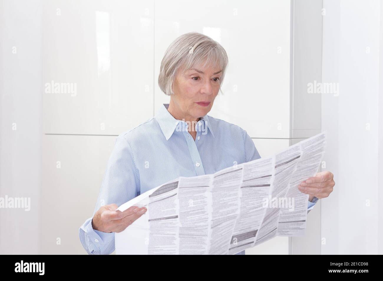 Ältere Frau mit einem riesigen Patienteninformationsblatt für ihre verschriebene Medizin, Platz zum Kopieren. Stockfoto