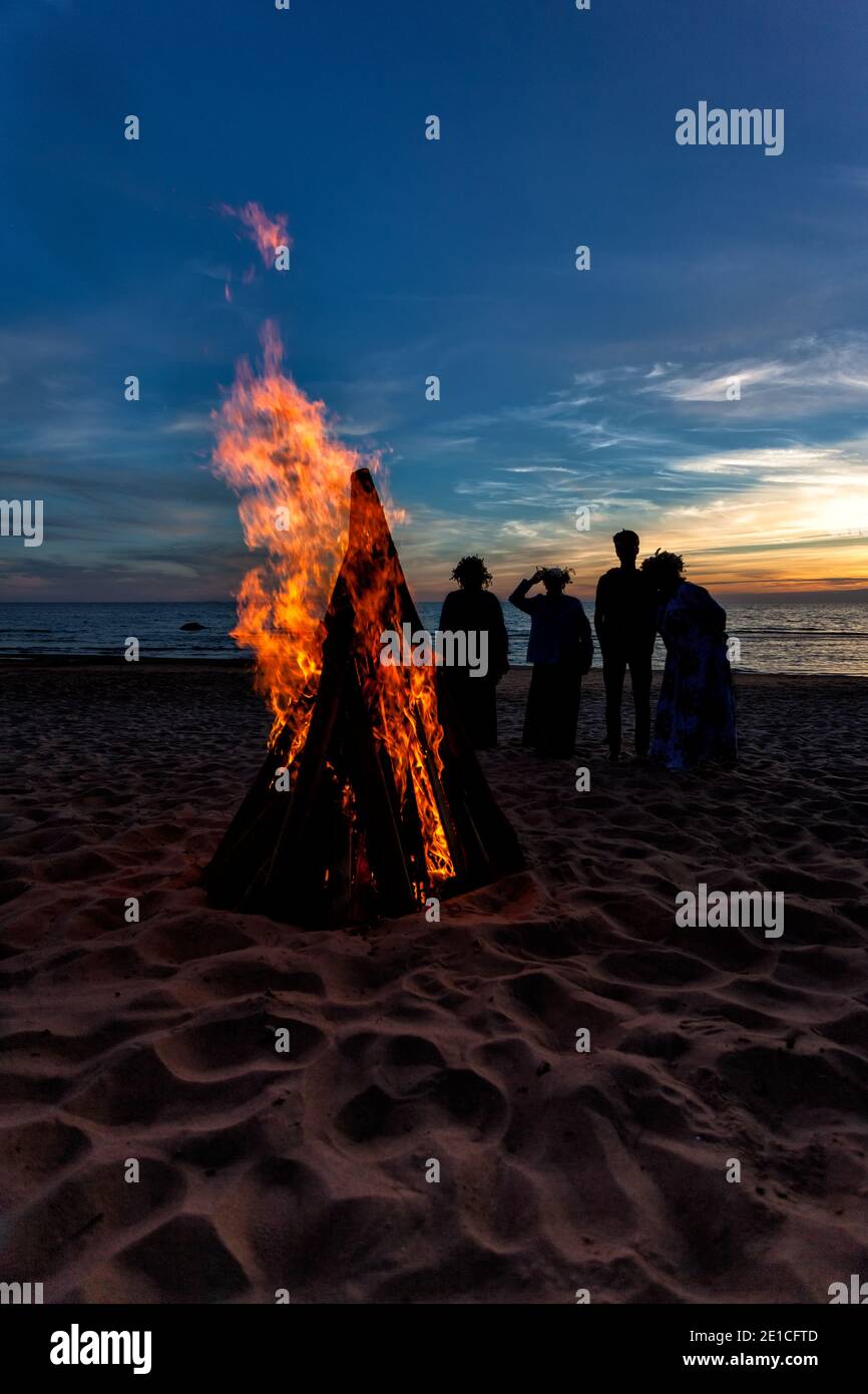 Nicht erkennbare Menschen feiern Sommersonnenwende mit Lagerfeuer am Strand Stockfoto