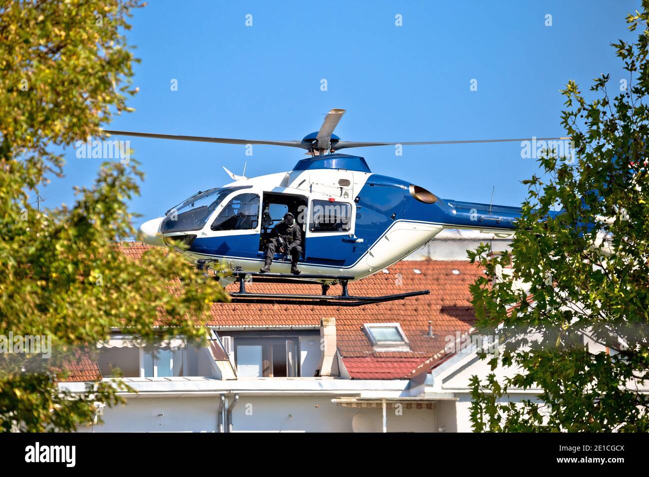 Polizei Scharfschütze im Hubschrauber städtischen Bereich niedrigen Flug Ansicht, maskiert und nicht erkennbar spezielle Luftstreitkräfte in Aktion Stockfoto