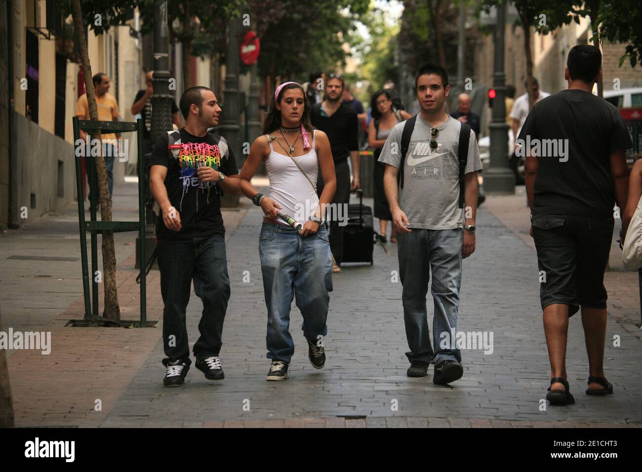 Fußgänger, die entlang einer von Bäumen gesäumten Straße spazieren. Calle de las Huertas in Madrid. Stockfoto