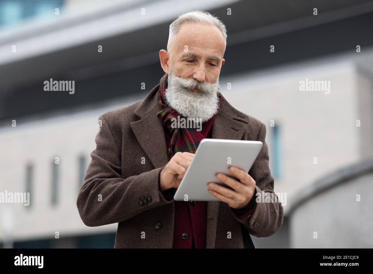 Wohlhabender älterer Mann mit digitalen Tablet im Freien Stockfoto
