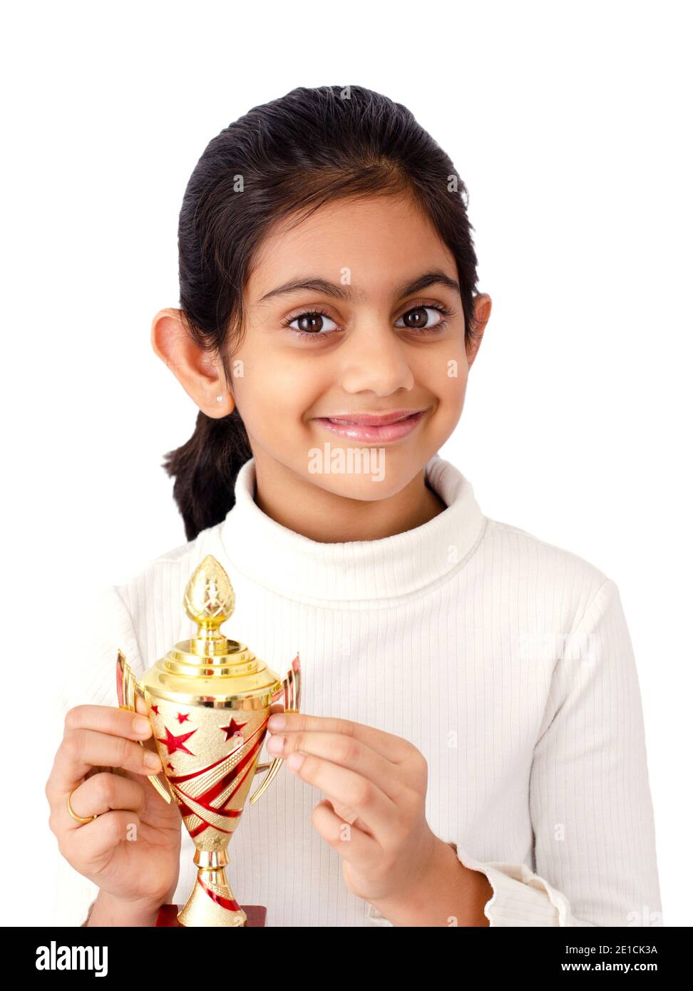 Porträt eines kleinen indischen Mädchen in weißem Hintergrund mit goldene Gewinner Trophäe in der Hand Darstellung Sieg Symbol Stockfoto