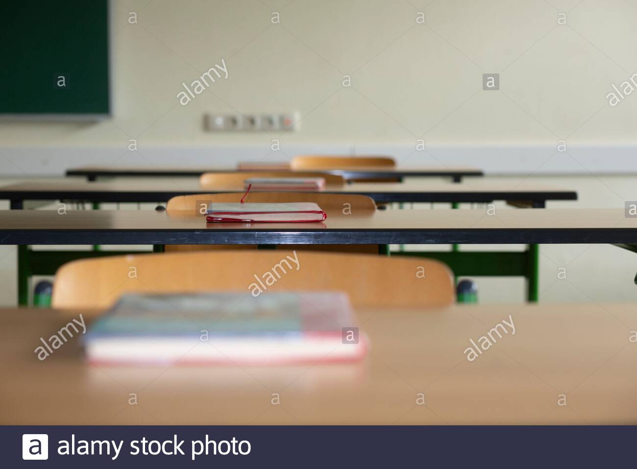 Eine Reihe von Schulbüchern auf einem Tisch in einem verlassenen Klassenzimmer, während die Corona-Krise andauert. Stockfoto