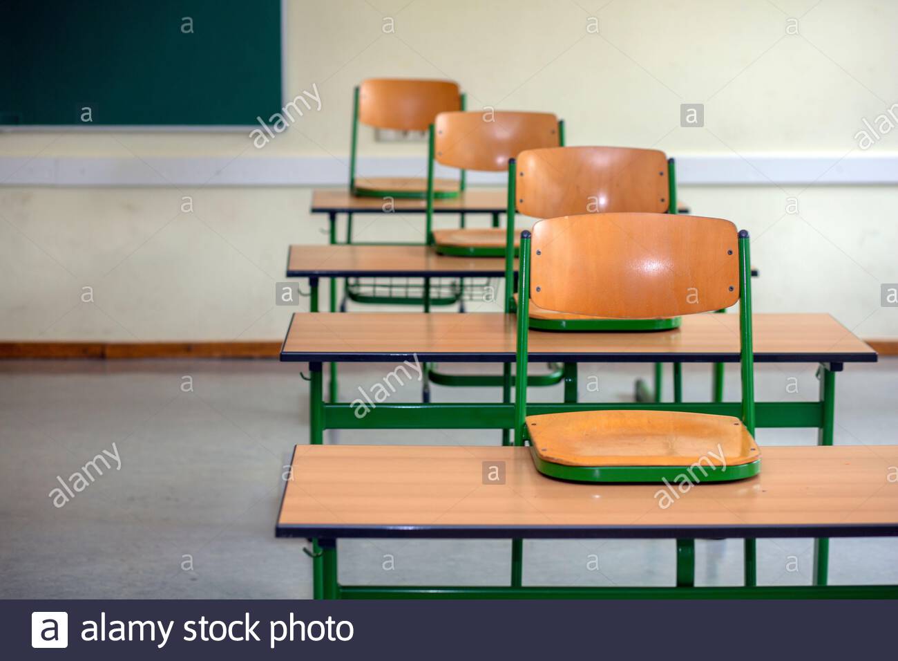 Ein Satz von Stühlen auf der Schule deaskiert in einem verlassenen Klassenzimmer als die Corona-Krise weiter. Stockfoto