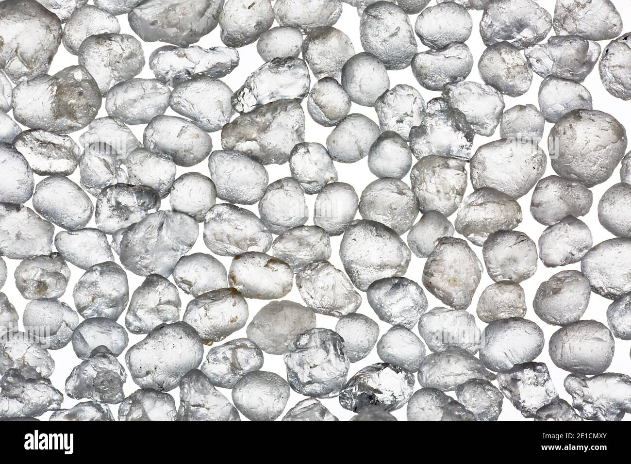 Makrobild von Körnern von Wanipigow White Sand, fotografiert mit 5facher Vergrößerung auf weißem Hintergrund. Stockfoto