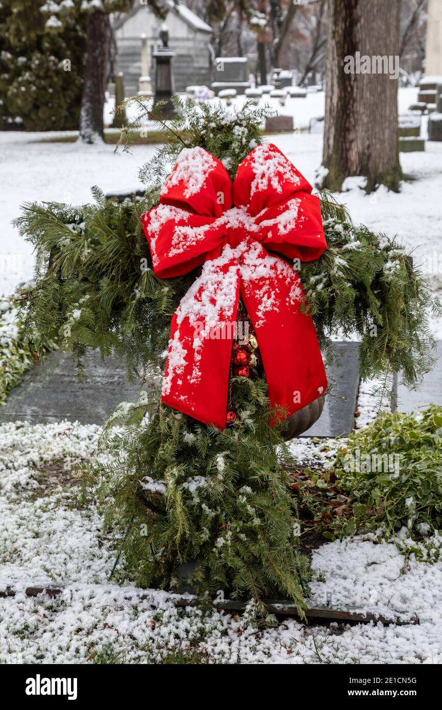 Detroit, Michigan - Weihnachtsgrün und ein roter Bogen auf einem Grab nach einem Schneefall in Elmwood Cemetery. Stockfoto