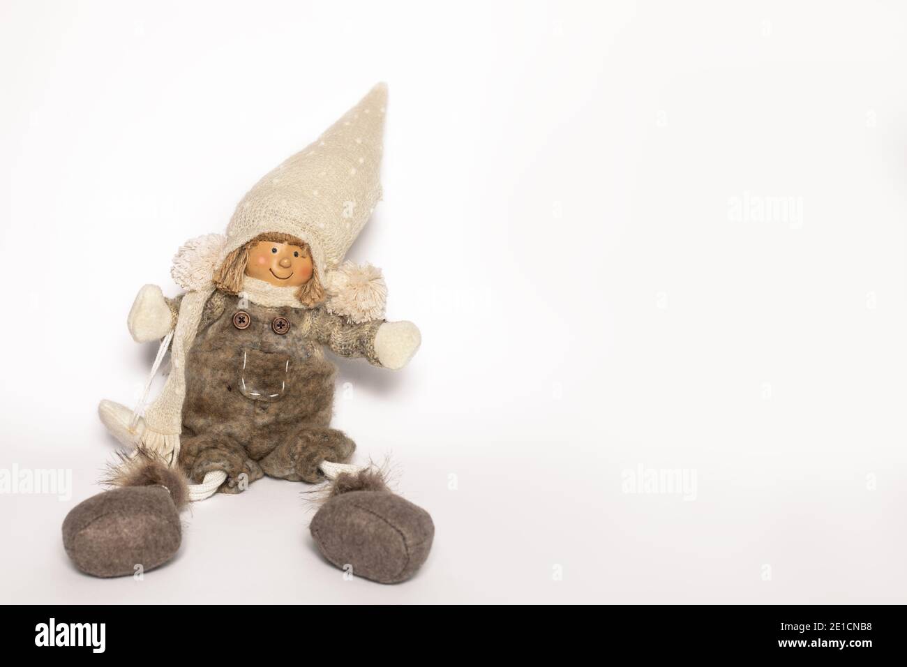 Handwerk Puppe Mädchen in warmen Kleidern und handgefertigten Hut sitzt auf weißem Hintergrund mit Copy Space. Vorderansicht Stockfoto