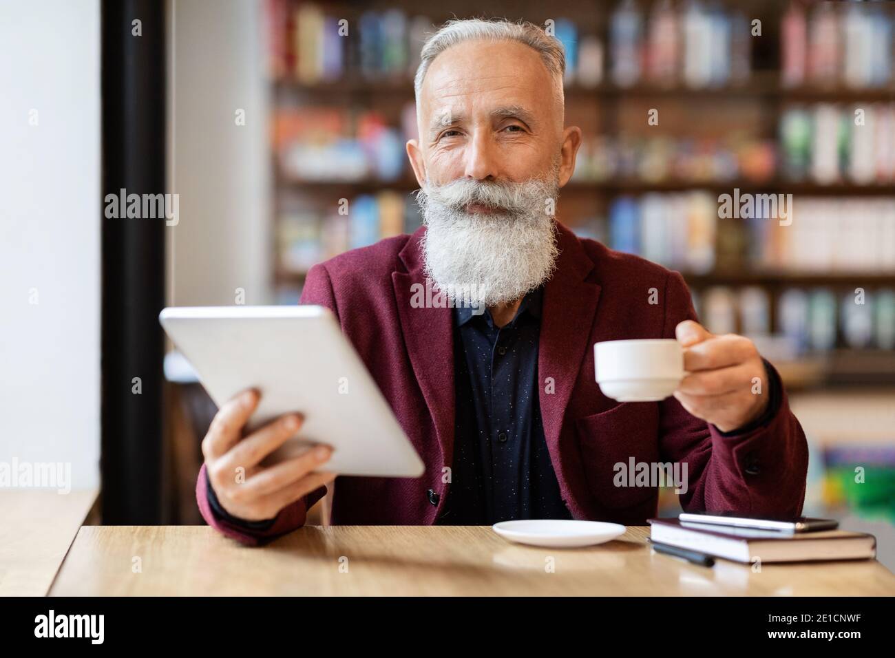 Wohlhabender Geschäftsmann trinken Kaffee und mit digitalen Tablet Stockfoto