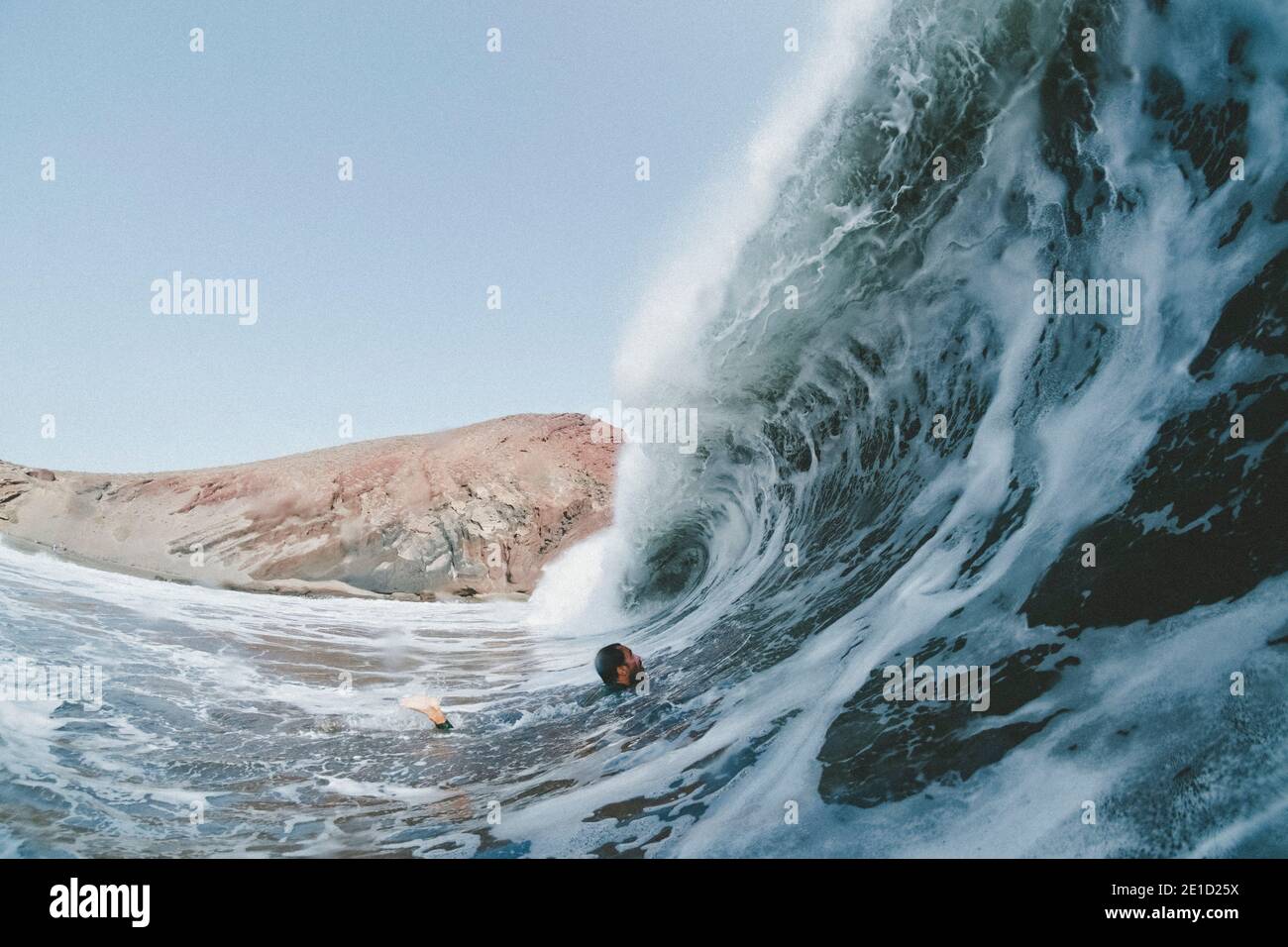 Mann schwimmt unter einer großen, plätschernden Meereswelle, Playa de la Tejita, Teneriffa, Spanien Stockfoto