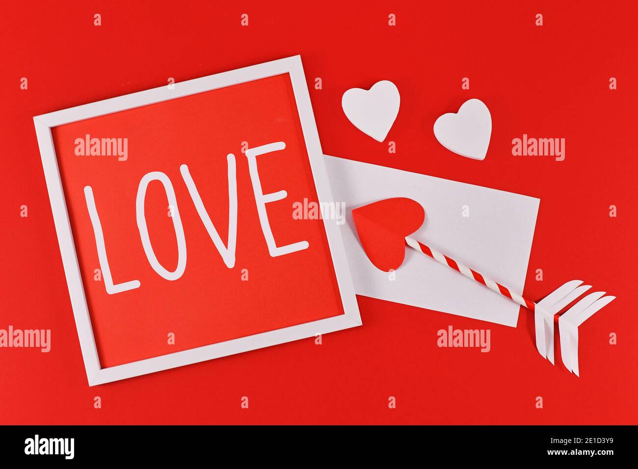 Valentine's Day Komposition mit Bilderrahmen mit Text "LIEBE", Amor Liebe Pfeile, Brief und Herzen auf rotem Hintergrund Stockfoto