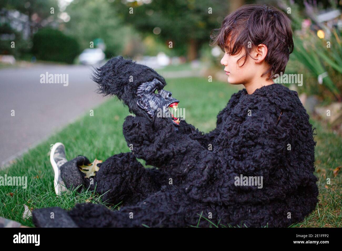 Ein Junge sitzt im Gras im Gorilla Anzug und schaut zu Gruselige Gorilla  Maske Stockfotografie - Alamy