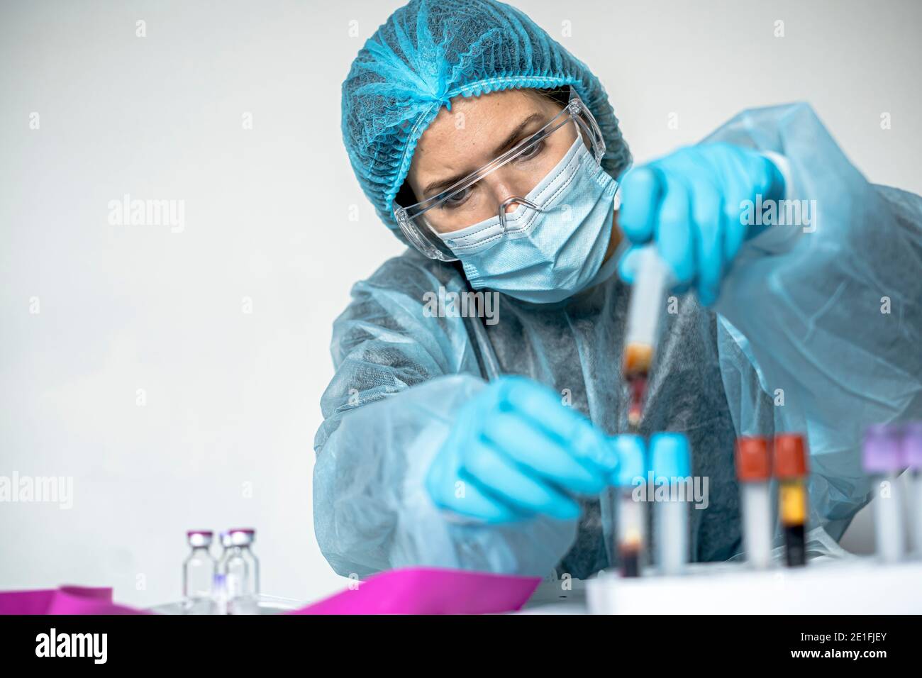 Blutteströhre mit Etikett von Covid-19 auch bekannt als Coronavirus oder neuartige Corona in Wissenschaftler Hand im Labor. Wissenschaftlerin trägt hoch p Stockfoto