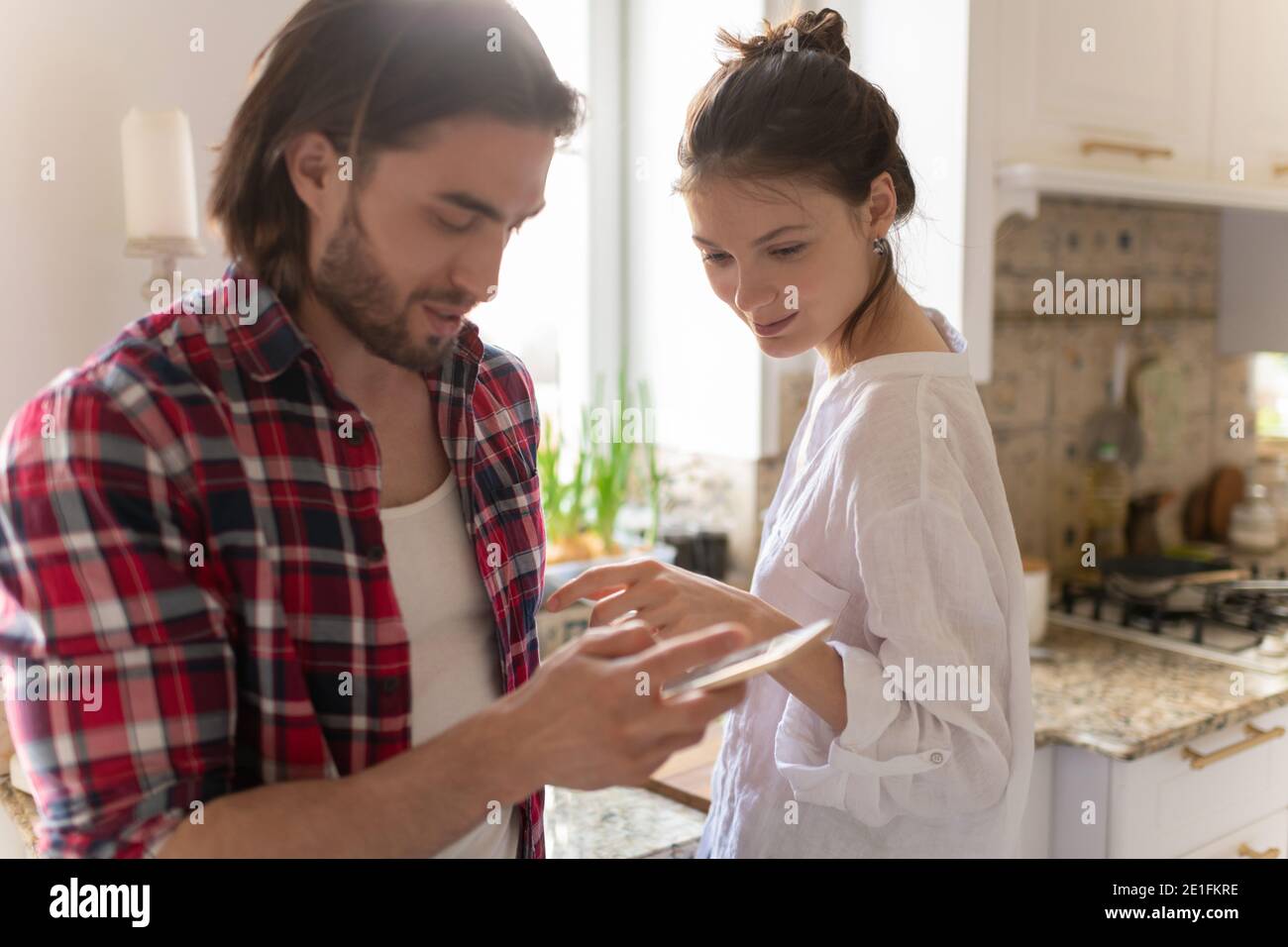 Mann teilt Daten auf dem Smartphone mit Frau beim Kochen Essen In der Küche zusammen Stockfoto