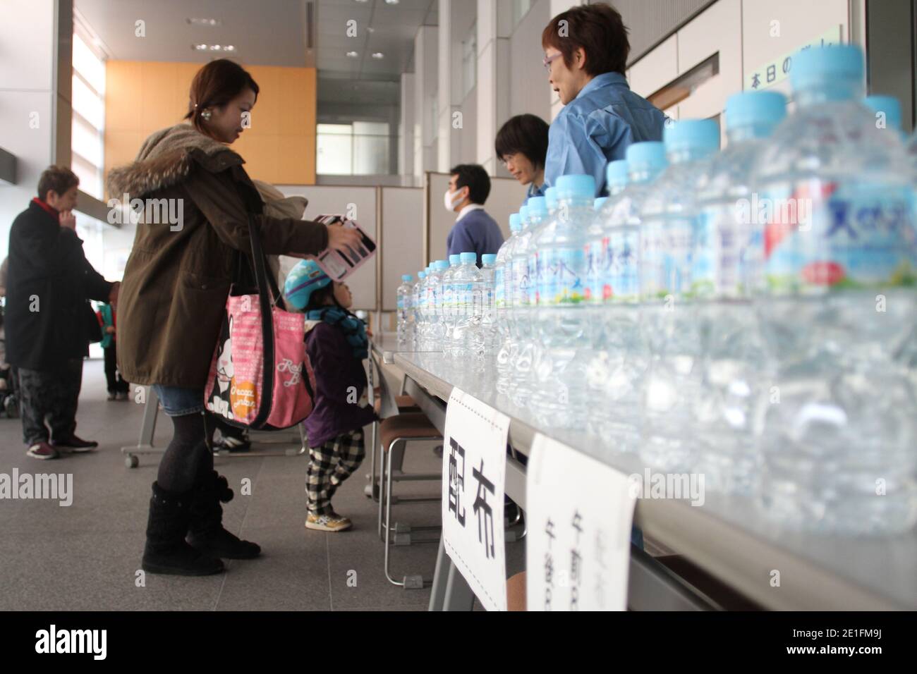 Mütter mit Kleinkindern nehmen im Suginami-Gesundheitszentrum in Ogikubo, Abteilung Suginami im Westen Tokios, Wasser in Flaschen auf, nachdem am 22. März 2011 festgestellt wurde, dass das Wasser in der beschädigten Atomanlage von Fukushima in Tokio, Japan, mit radioaktivem Jod 131 kontaminiert war. Der panische Kauf wurde erst durch die Nachricht am Mittwoch ausgelöst, dass die Kläranlage Kanamachi, die 2.35 Millionen Einwohner Tokios versorgt, einen Wert von 210 Becquerels pro Kilogramm verbucht hatte. Der Messwert betrug mehr als das Doppelte der japanischen Sicherheitsgrenze für den Verzehr durch Säuglinge, aber weit im akzeptablen Bereich für Erwachsene Stockfoto